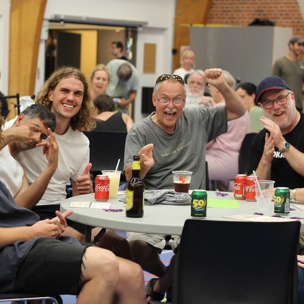 En gruppe deltagere ved spisebordet og ser glade ud og vinker
